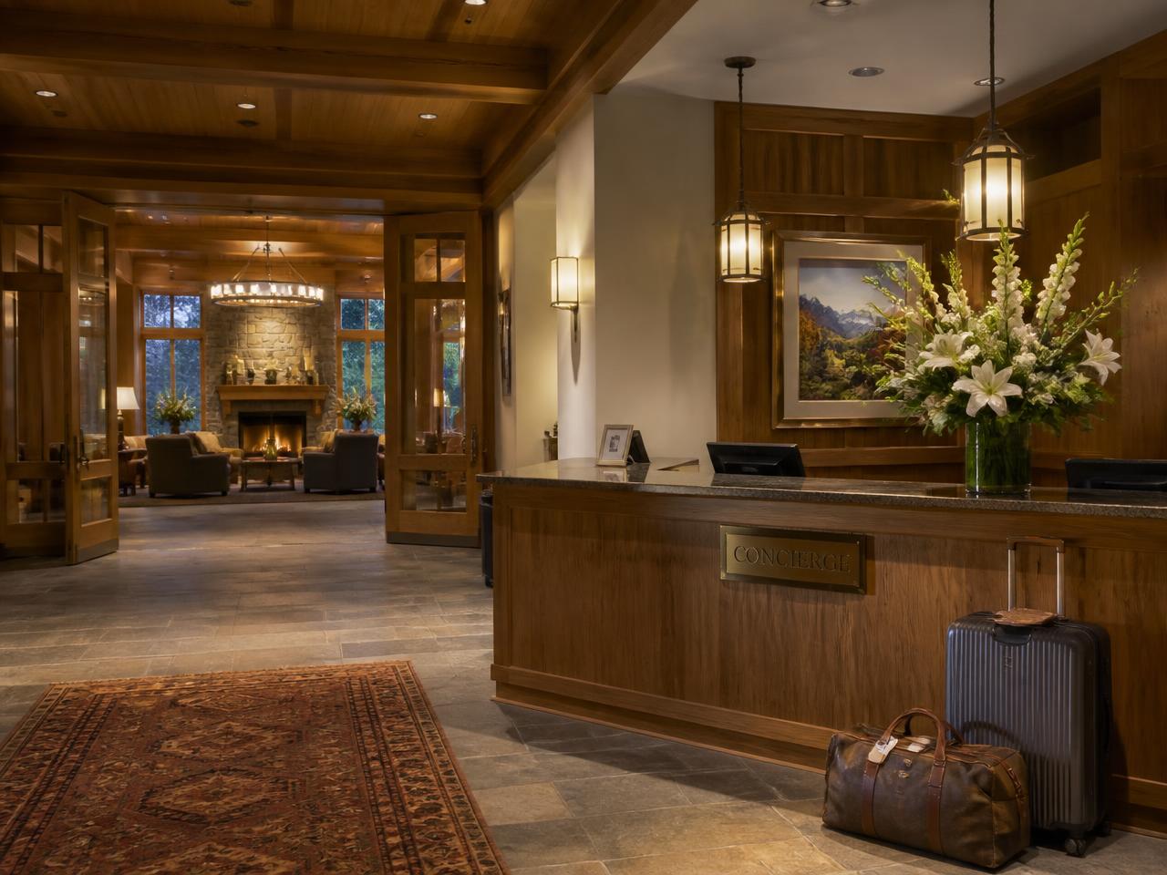 Warm lodge concierge desk with fresh flowers and luggage waiting nearby